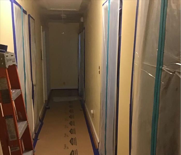 Hallway with clear containtment installed on five doorways within hallway.  Blue and green masking tape used to seal. 