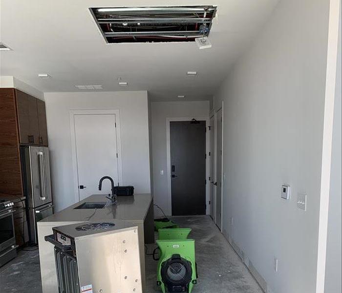 SERVPRO drying equipment four green air movers and one steel dehumidifier. Grey floor removed and cut drywall. 