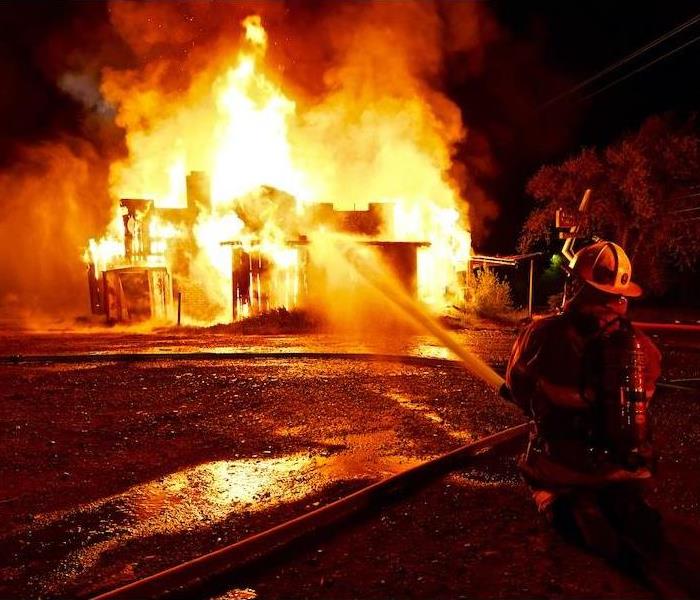 a large building fire trying to be put out by a firefighter at night