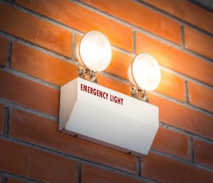 emergency light hanging on an interior red brick wall